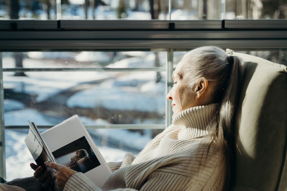 A woman reading in an armchair by a sunlit window
